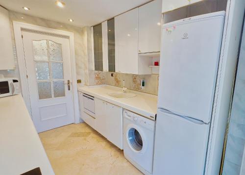 a kitchen with a white refrigerator and a washing machine at Parque Marbella Three Bedroom Apartment in Marbella