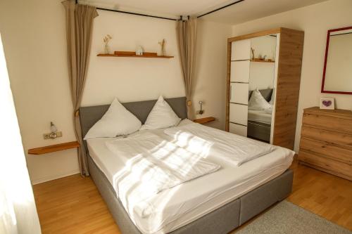 a bedroom with a bed with white sheets and a mirror at Ferienwohnung Schwarzalb in Untere Mühlbauern