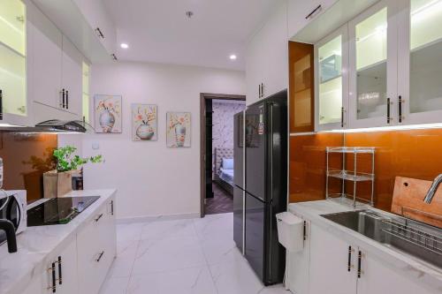 a kitchen with white cabinets and a black refrigerator at Shi House -Modern Luxury 2BR Apartment BE3 Beverly in Ấp Thạnh Lộc