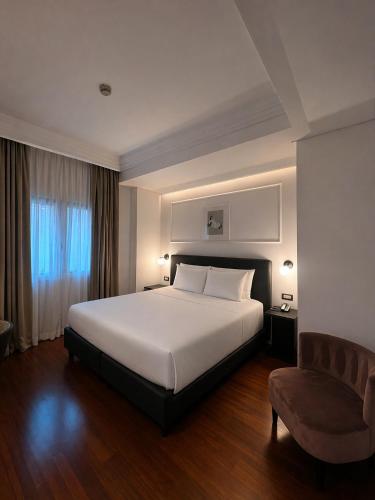 a bedroom with a large white bed and a chair at BB Hotels Smarthotel Missori in Milan