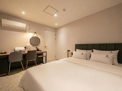 a bedroom with a white bed and a desk and a desk at Busan Station Iruda Hotel in Busan