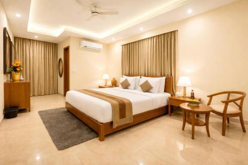 a bedroom with a bed and a table and a chair at Hotel Viva Palace By OPO Delhi Airport in New Delhi