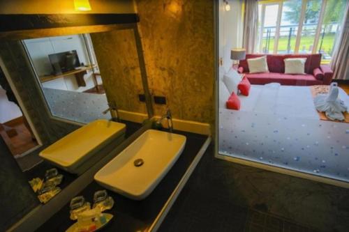 a bathroom with a sink and a mirror and a couch at Barn Talaepu Resort in Ban Suan Khat