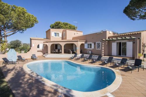 a villa with a swimming pool in front of a house at Villa Anita by Algarve Holidays in Quarteira