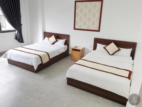 two beds in a room with white walls at Vy An Hotel in Bảo Lộc