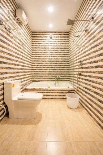 a bathroom with a toilet and a bath tub at Hotel Viva Palace By OPO Delhi Airport in New Delhi