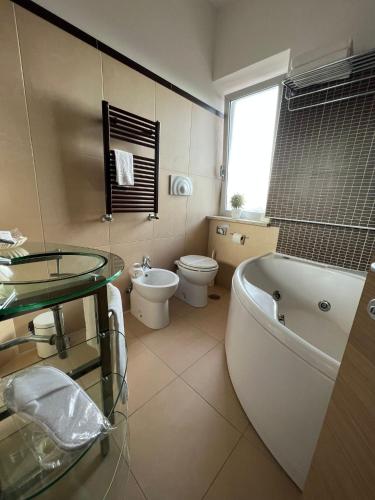 a bathroom with a tub and a toilet and a sink at Hotel Hermitage in Qualiano