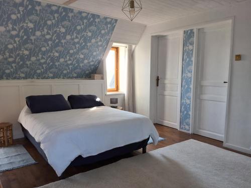 a bedroom with a bed with a blue and white wallpaper at Le Marronnier in Montchauvet