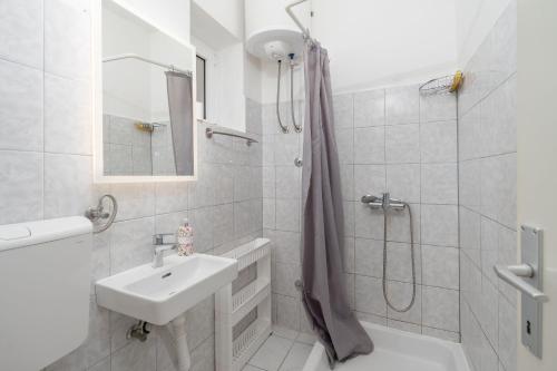a white bathroom with a sink and a shower at Apartments Zeljko in Pag