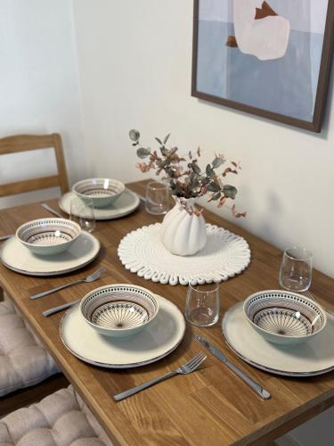 a wooden table with plates and a vase of flowers at Malūno namai 2 in Palanga