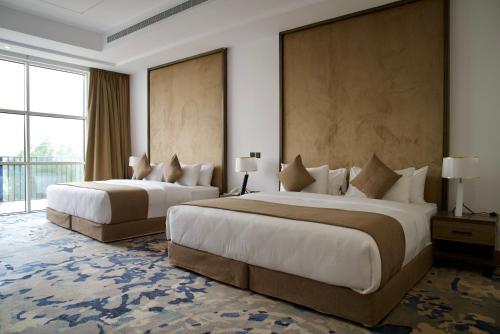 a hotel room with two beds and a large window at Alammariah Hills Resort- Riyadh in Diriyah