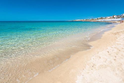 a sandy beach with the ocean in the background at Residence Salento Fronte Mare - Coste del Sud it in Torre San Giovanni Ugento