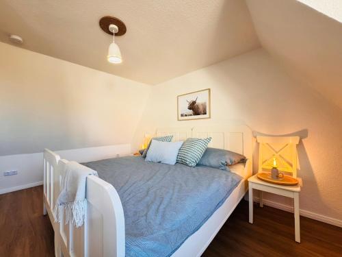 a bedroom with a white bed with blue pillows at Nordkiek No 8 Für 4 Person mit Meerblick in Westerholz