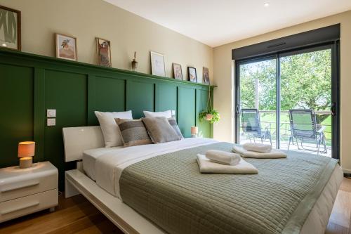 a bedroom with a large bed with a green headboard at L'Evasion, Piscine et jacuzzi in Lescherolles