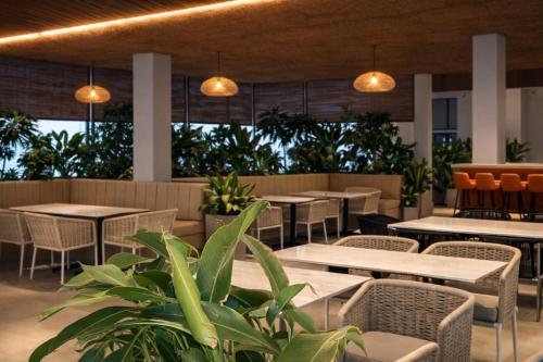 a restaurant with tables and chairs and plants at Chethan International in Bangalore