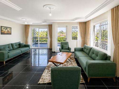 a living room with green couches and a table at Begonville Villas Ladies Beach in Kuşadası