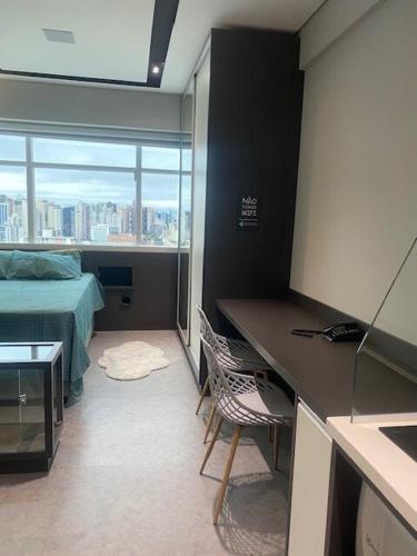 a room with a bed and a desk and a bed and a window at Studio Centro Curitiba - para ate 3 pessoad in Curitiba