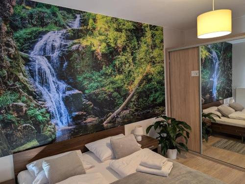 a bedroom with a waterfall mural on the wall at Apartament Góry Las in Szklarska Poręba