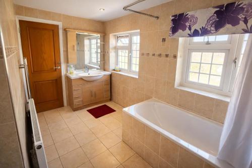 a bathroom with a tub and a sink and a mirror at Value Stay Comfortable Rooms Windsor Legoland Heathrow in Windsor