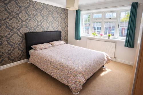 a bedroom with a bed and two windows at Value Stay Comfortable Rooms Windsor Legoland Heathrow in Windsor