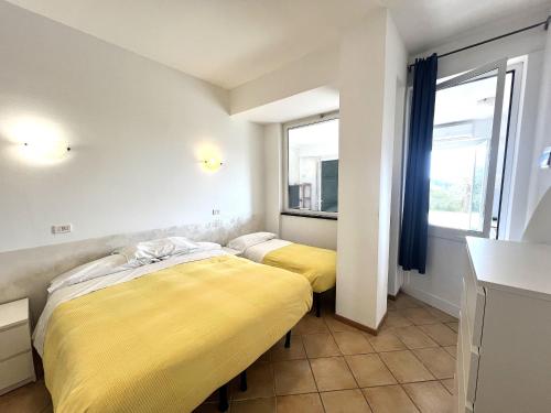 two beds in a room with yellow sheets at Appartamento Nettuno in Villa Daria a 2 Km dal mare golfo del Tigullio in Chiavari