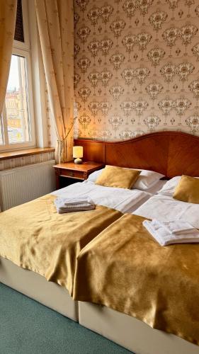 a large bed in a bedroom with a window at Hotel MERTIN in Chomutov