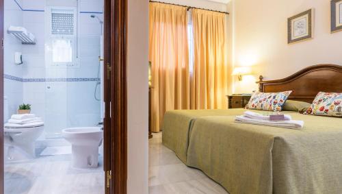 a bedroom with a bed and a shower and a toilet at Hotel Gran Avenida in Coria del R&iacute;o