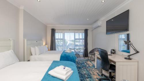 a hotel room with two beds and a desk at Stonehouse on Main in Struisbaai