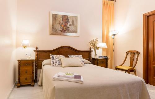 a bedroom with a bed and a chair at Hotel Gran Avenida in Coria del R&iacute;o