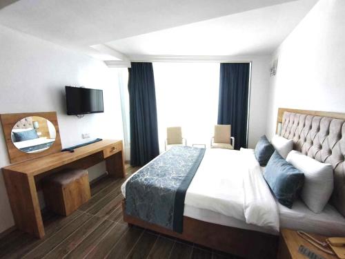 a hotel room with a bed and a television at BEACHFRONT SUNPORT BOUTIQUE Hotel & Restaurant in Kyrenia