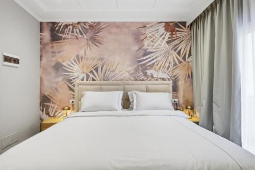 a bedroom with a white bed and a tropical wallpaper at Hotel Giulia in Durrës
