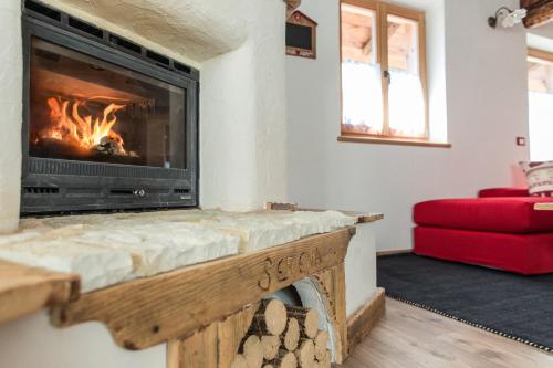 a living room with a fireplace and a red couch at Maso Del Fieno con Sauna Privata e Vista Unica in Sant'Orsola Terme