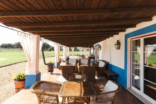 a patio with wicker chairs and tables on a porch at Charming Farm House With Pool in Ferreira do Alentejo