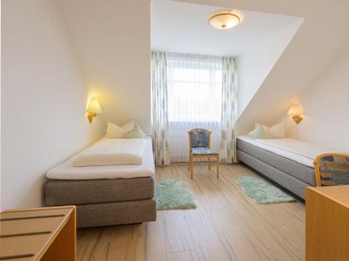 a small room with two beds and a chair at Hotel Restaurant Bergeshöhe in Mettingen