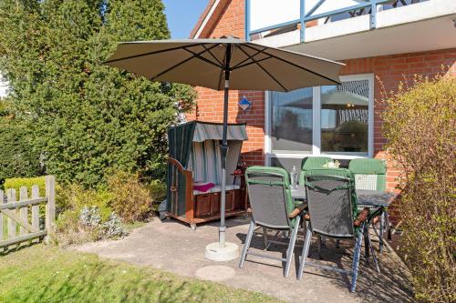 a table and chairs under an umbrella on a patio at Strandlächeln in Neue Tiefe Fehmarn