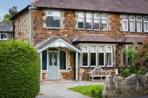 a brick house with a white door and a bench at The Kingsway in Ilkley