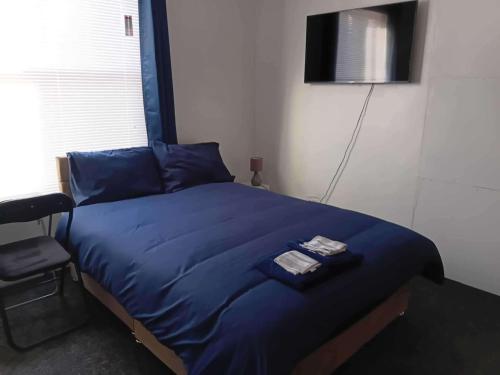 a bedroom with a blue bed with a television on the wall at Sleeps 2 - Parking - Wifi in Oldbury