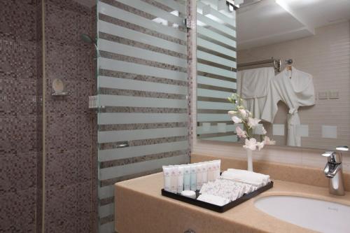 a bathroom with a sink and a mirror at Corniche Hotel Al Khobar in Al Khobar