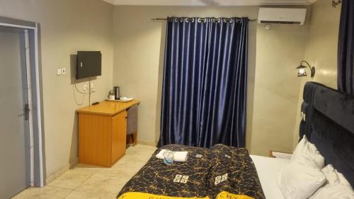 a bedroom with a bed and a tv and a window at Davic-lite hotel and suites in Okitipupa