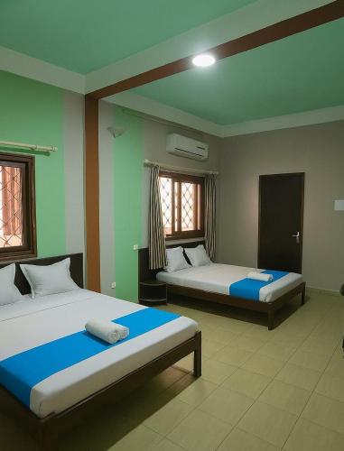 a bedroom with two beds and two windows at L'Hotel 5-5 in Mahajanga