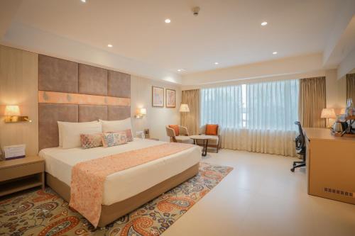 a hotel room with a large bed and a desk at Grand Mercure Vadodara Surya Palace in Vadodara
