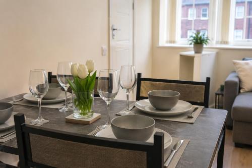 a dining room table with wine glasses and flowers on it at Premium 2BR Retreat for Long Stays in Manchester