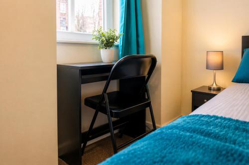 a black desk with a chair next to a window at Premium 2BR Retreat for Long Stays in Manchester