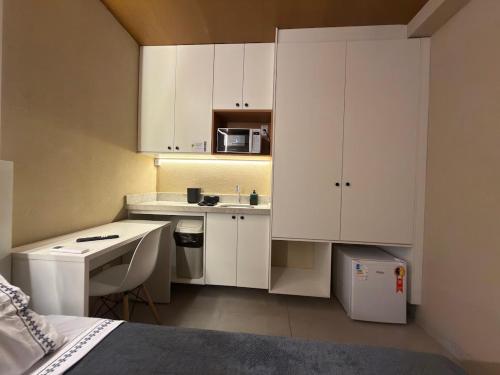a small kitchen with white cabinets and a bed at Studios 138 in Belém