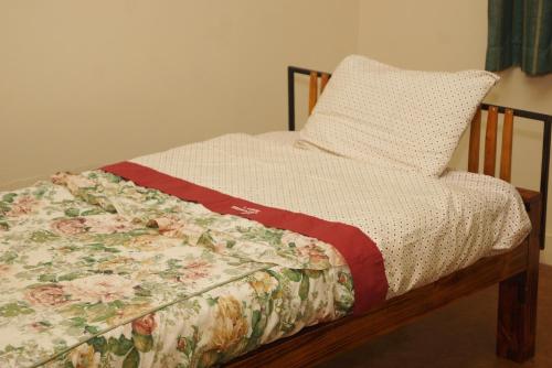 a bed with a floral quilt and a pillow on it at JMR Cottages in Kampala