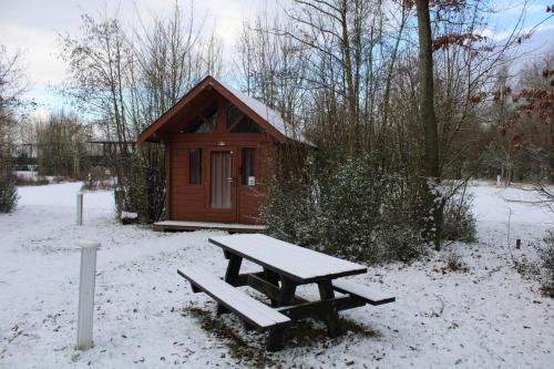 a picnic table in front of a cabin in the snow at Urban gardens Ieper - Basic blokhut in Ieper