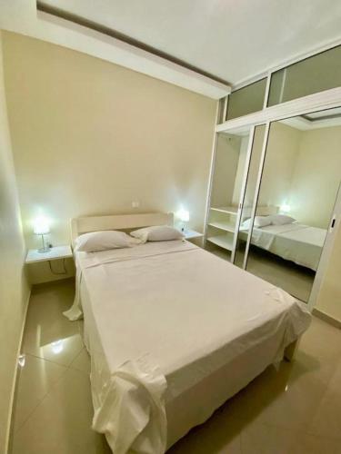 a bedroom with a large white bed and a mirror at Monte Do Bem-Estar Tarrafal in Tarrafal