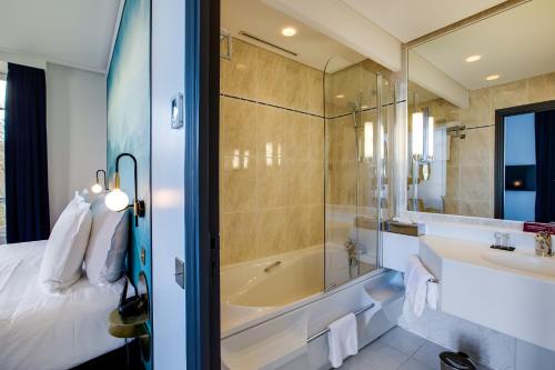 a bathroom with a bed and a tub and a sink at Le Palace de Menthon in Menthon-Saint-Bernard