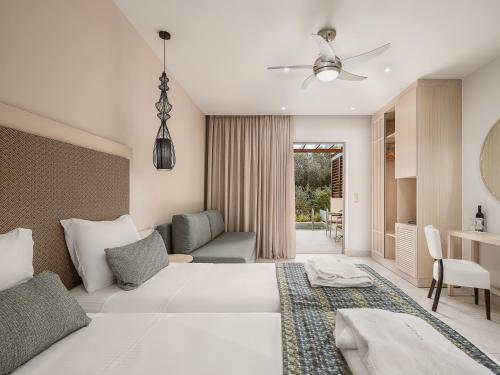 a bedroom with a white bed and a living room at Sirios Village Hotel & Bungalows - All Inclusive in Kato Daratso