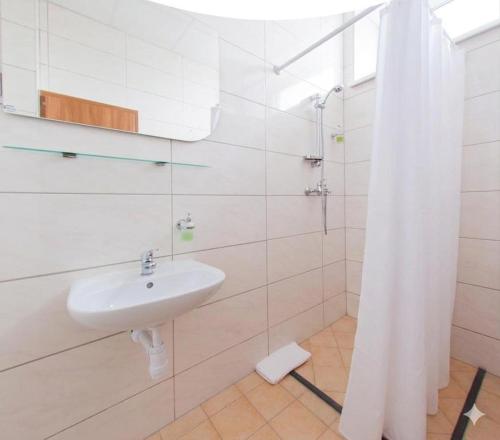 a white bathroom with a sink and a shower at Air Kaunas in Karmėlava